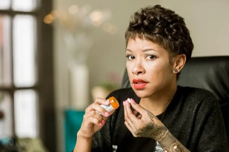 Nervous looking woman holds fentanyl pill in her hand