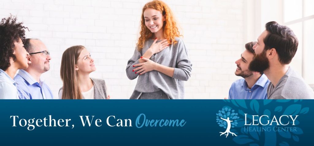 a woman in a group therapy session holding her hand on her chest as she speaks to other addicts about her recovery from anxiety and trauma